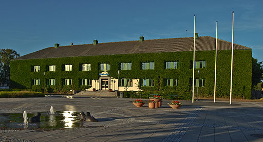 Bilden visa Ifö Sanitärs huvudkontor i Bromölla, en byggnad täckt med växtlighet. Framför huset finns ett torg med en fontän.